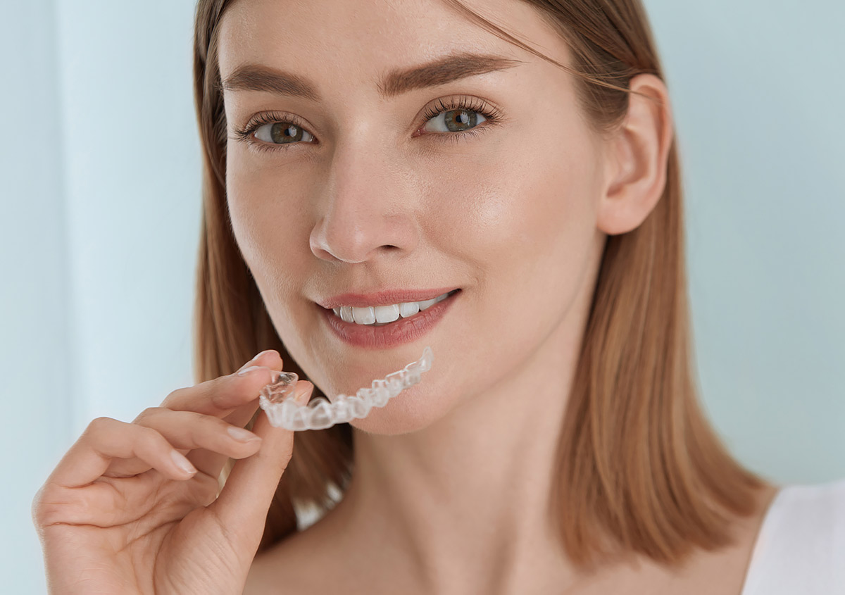 A beautiful woman holding a invisalign® clear aligners.