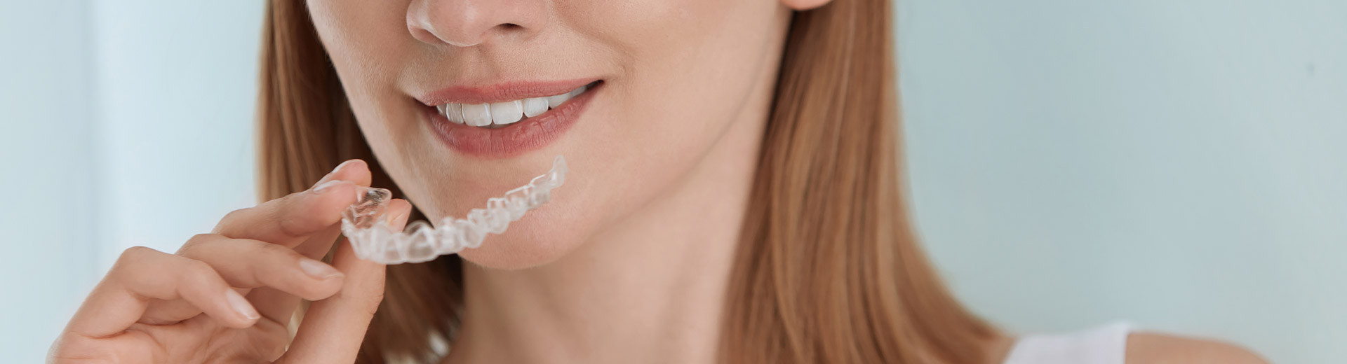 A woman is holding a Invisalign clear aligners.