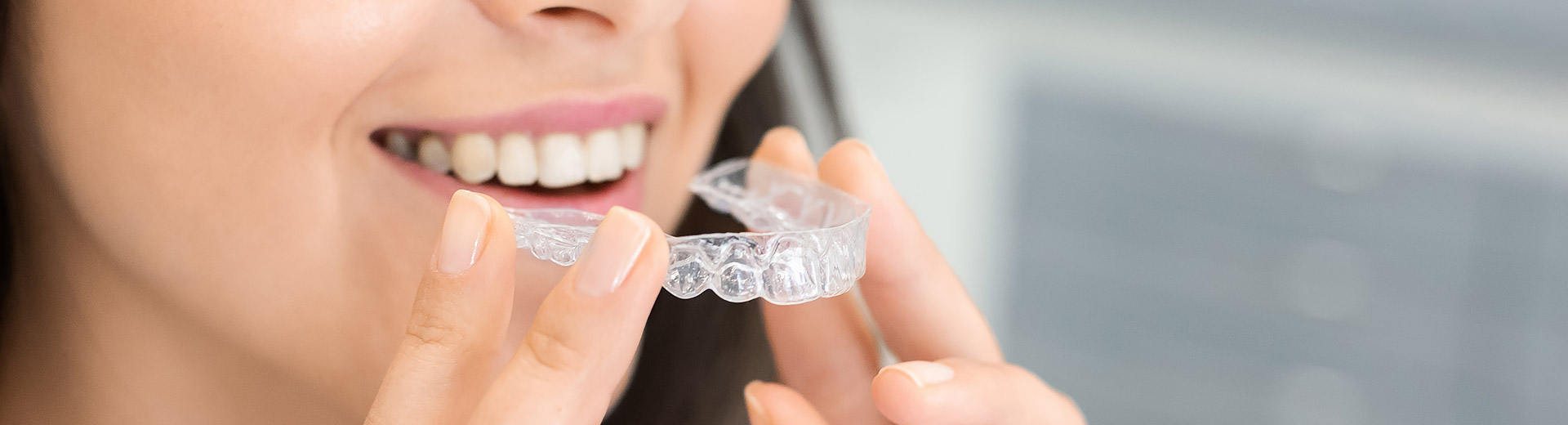 A woman is holding a Invisalign clear aligners.